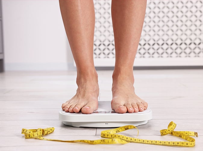 person weighing themselves on bathroom scales