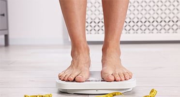 person weighing themselves on bathroom scales