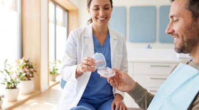 Sleep dentist handing a patient a custom oral appliance for sleep apnea