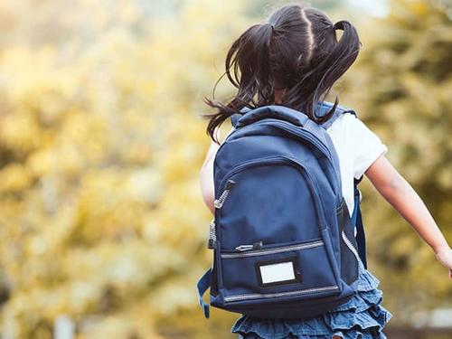 child wearing backpack after school